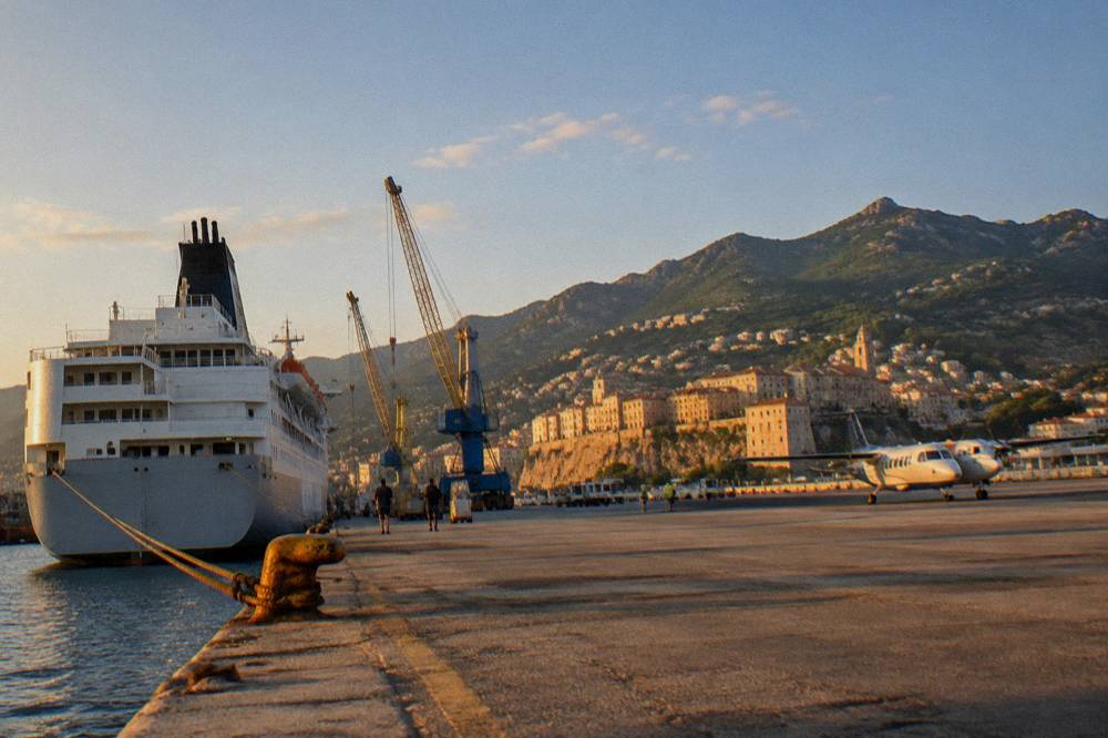 A small plane on a regional airport apron beside Mediterranean hills