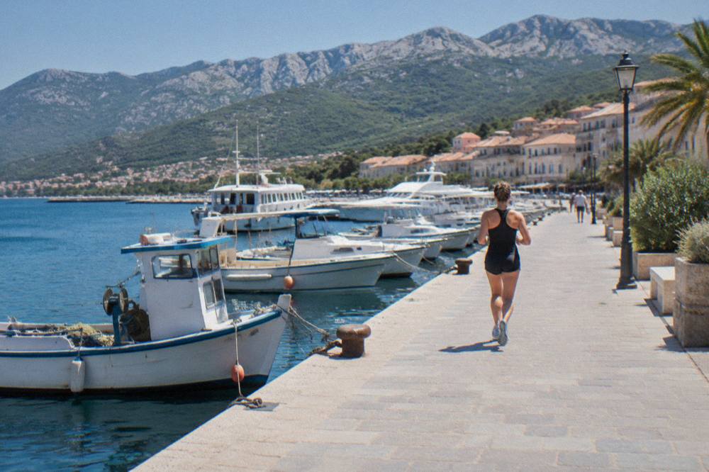 White boats moored in a small Corsican harbour town with hills behind