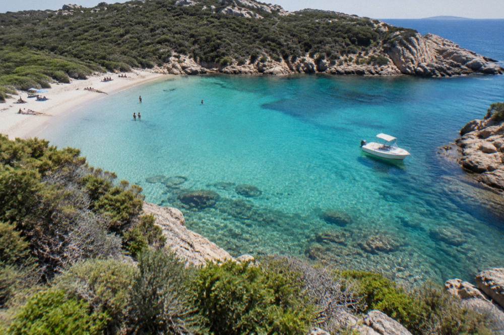 A small boat moored in a rocky cove with clear shallow water