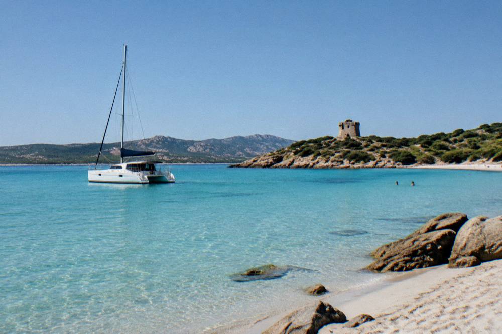 A catamaran moored in clear shallow water near white sand beaches
