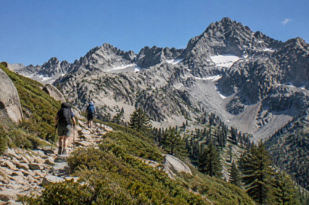 Hikers on a stone path toward rocky mountain peaks in central Corsica