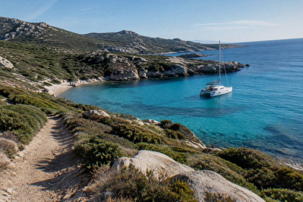 A catamaran moored in a turquoise cove along the Agriates coast near L'Île-Rousse