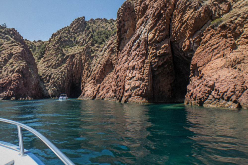A boat entering the red cliffs of the Scandola Nature Reserve on Corsica's west coast
