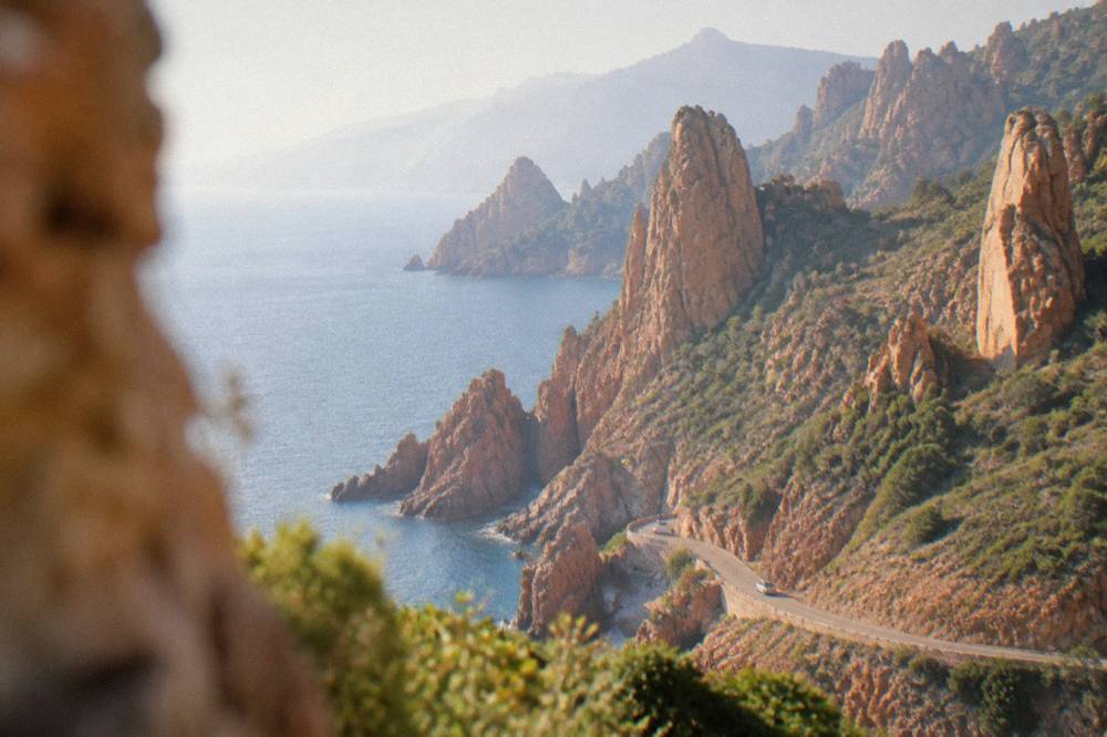 Red granite rock formations of the Calanques de Piana rising above the sea at golden hour