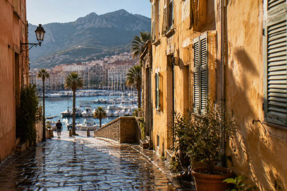 Wet cobbles and shuttered ochre facades after rain on a quiet Mediterranean street