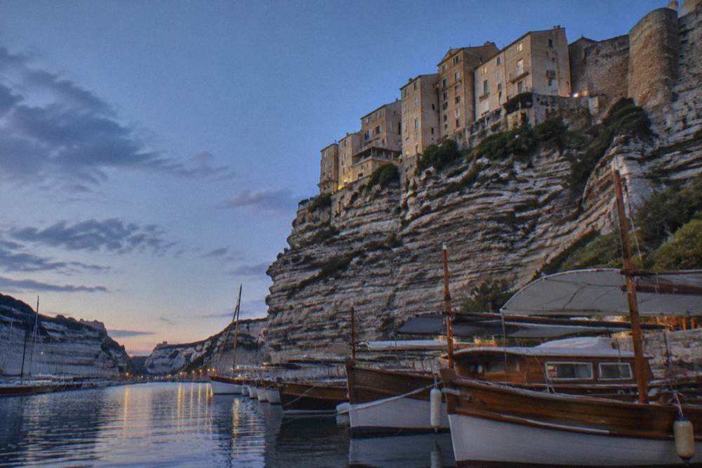 Wooden boats moored in Bonifacio's marina with white cliffs in the background
