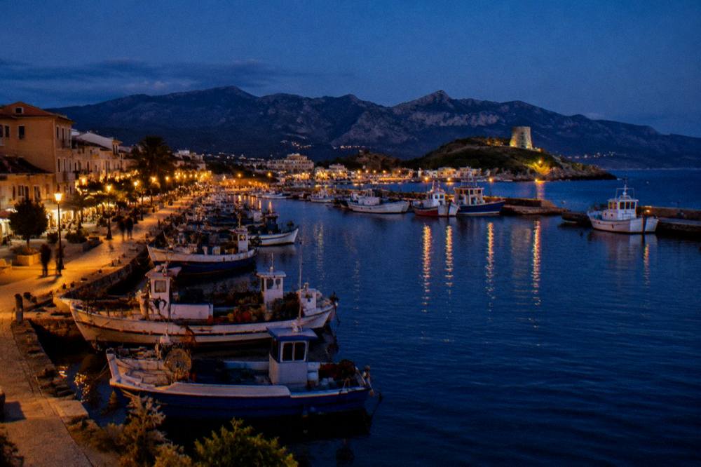 The harbour of Propriano at dusk with fishing boats and a lit waterfront