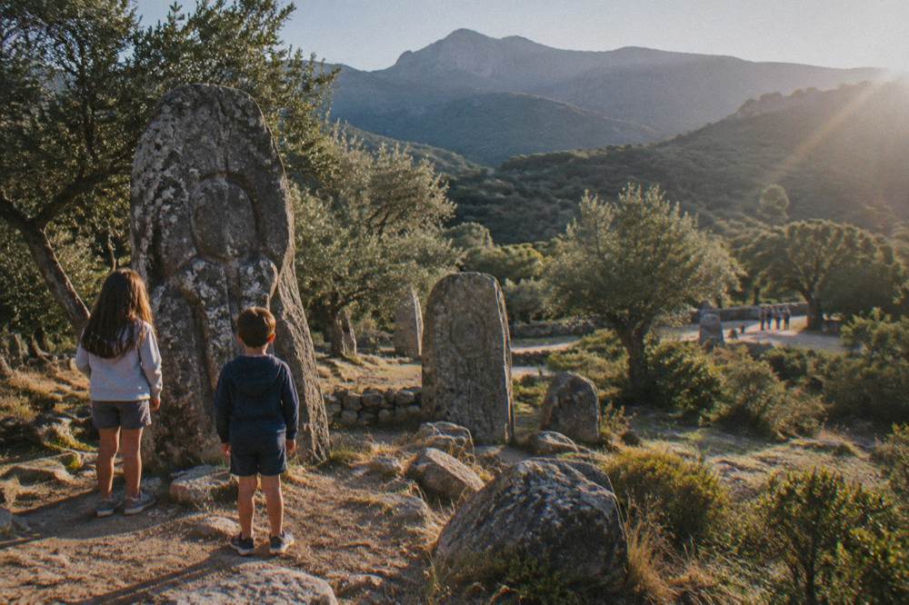 Children looking at carved prehistoric standing stones at an open-air Corsican site