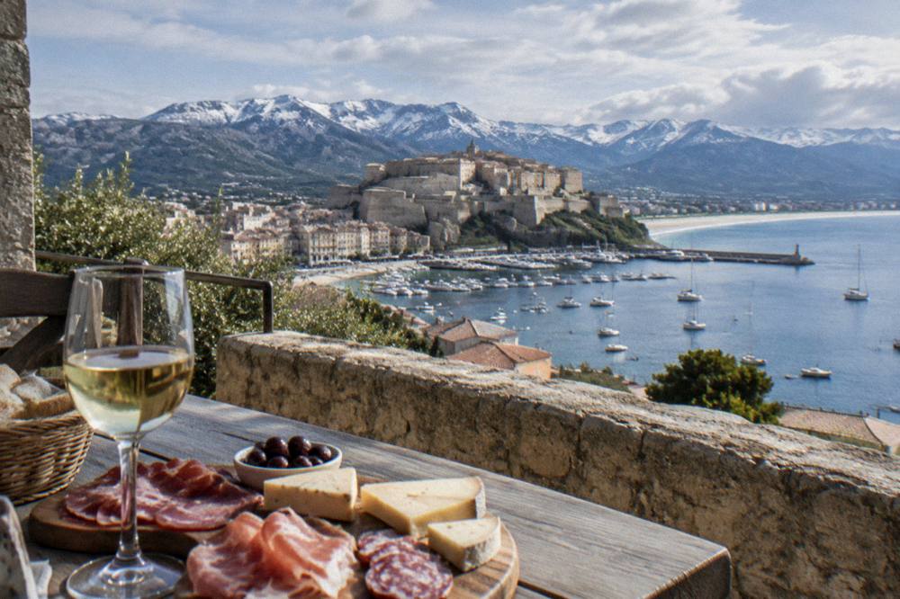 A table on a terrace with Corsican charcuterie, cheese and a glass of white wine