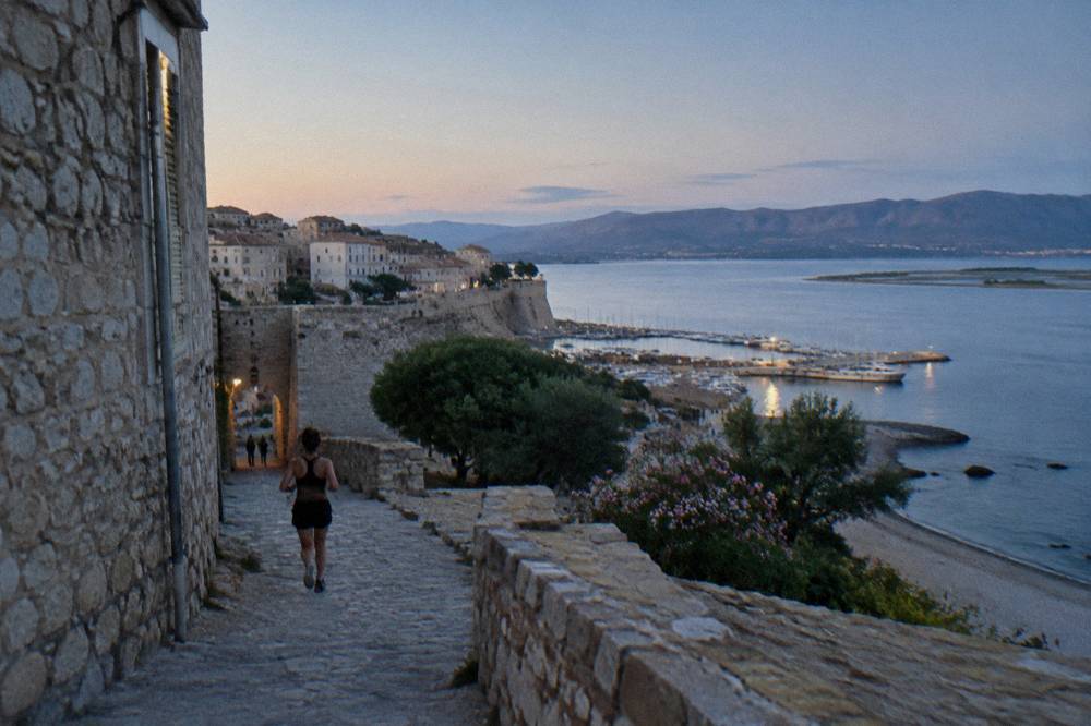 A stone village perched above the sea with a grey pebble beach below