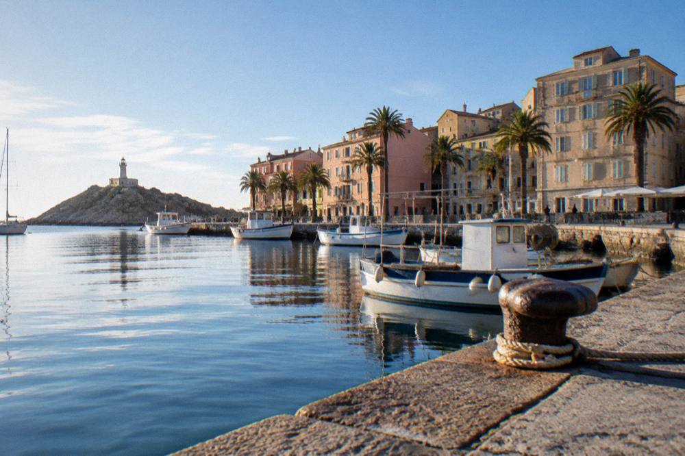 A Mediterranean old harbour with fishing boats moored beside pastel stone buildings