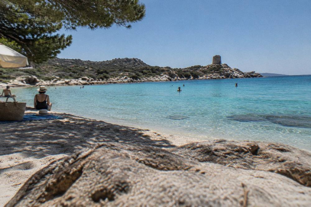 Calm turquoise sea at a rocky Corsican cove under a clear summer sky