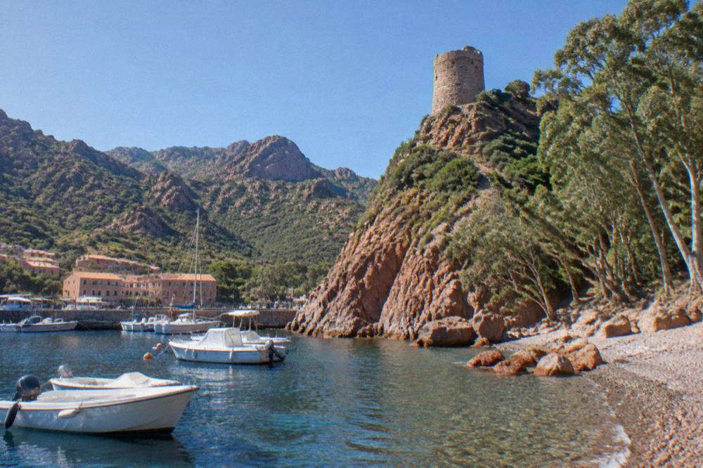 The small harbour of Porto on the Corsican coast with boats moored and hills behind