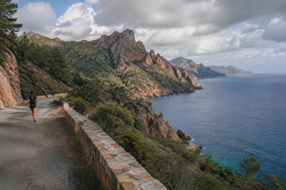 A winding coast road above red rocks and pine trees on the west coast of Corsica
