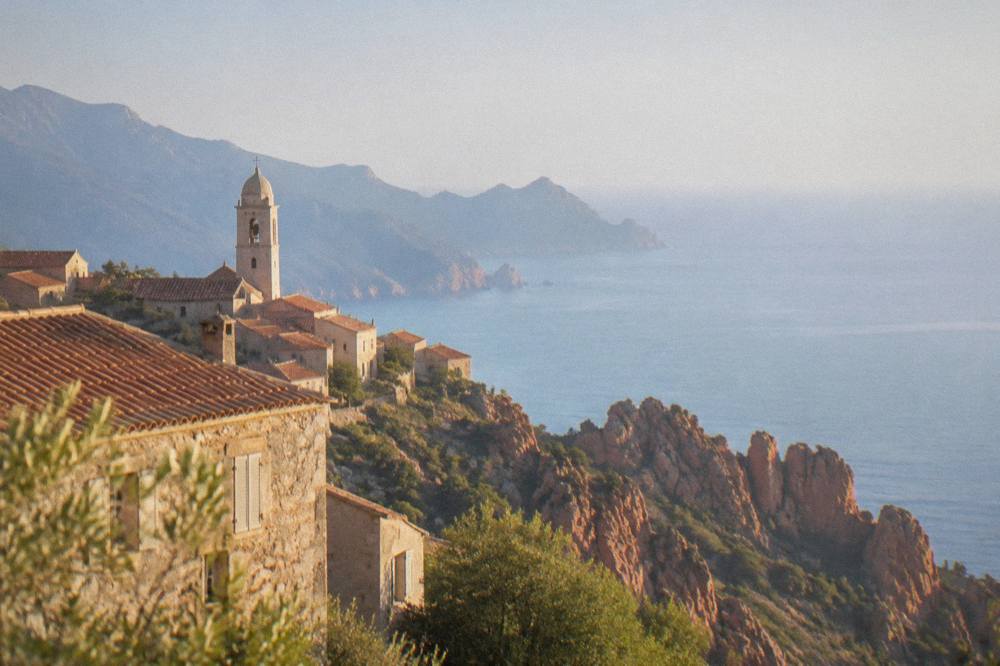 Sunset light on red granite rocks and calm sea near Piana in Corsica