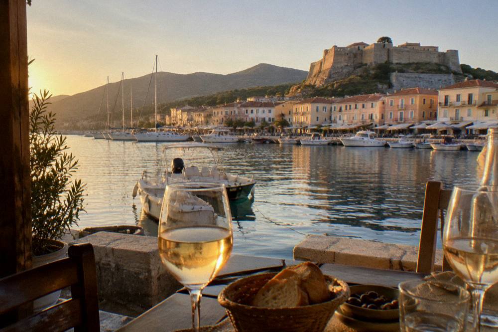 An evening table on a harbour terrace with wine, bread and a sea view