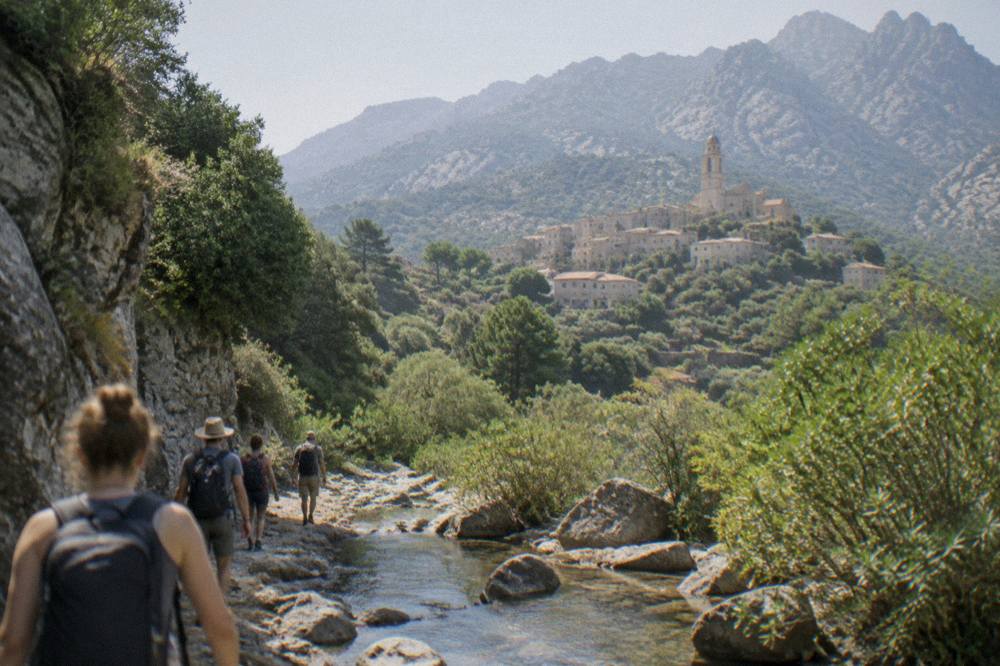A guide leading a small group along a stream in a narrow green granite canyon