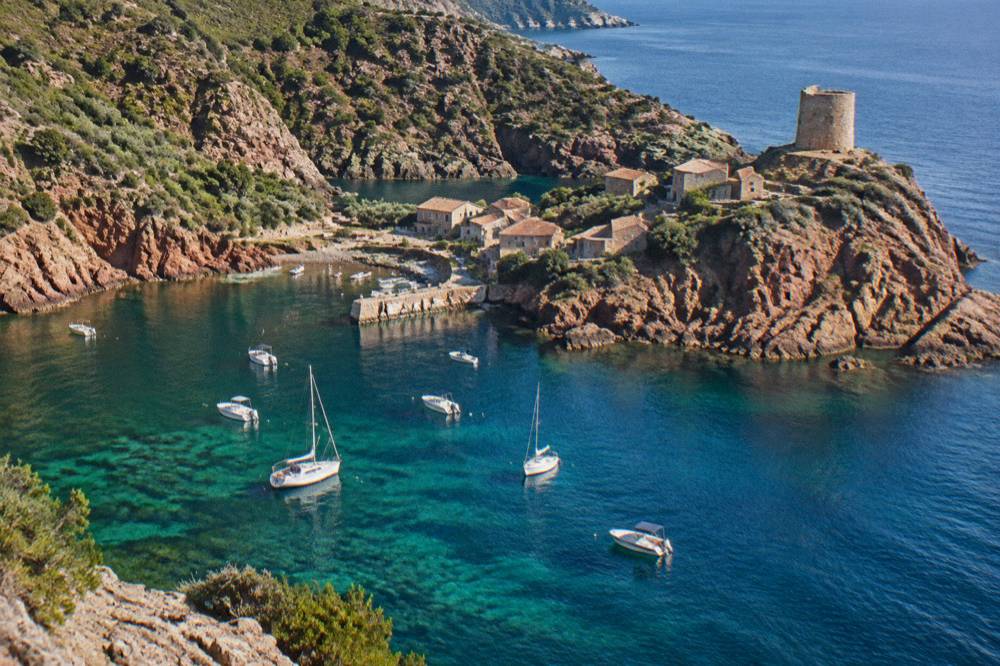 The small village of Girolata seen from the sea with boats at anchor in the cove