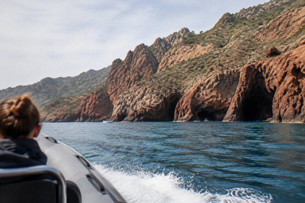 A semi-rigid inflatable boat at speed on open sea with coastline in the distance